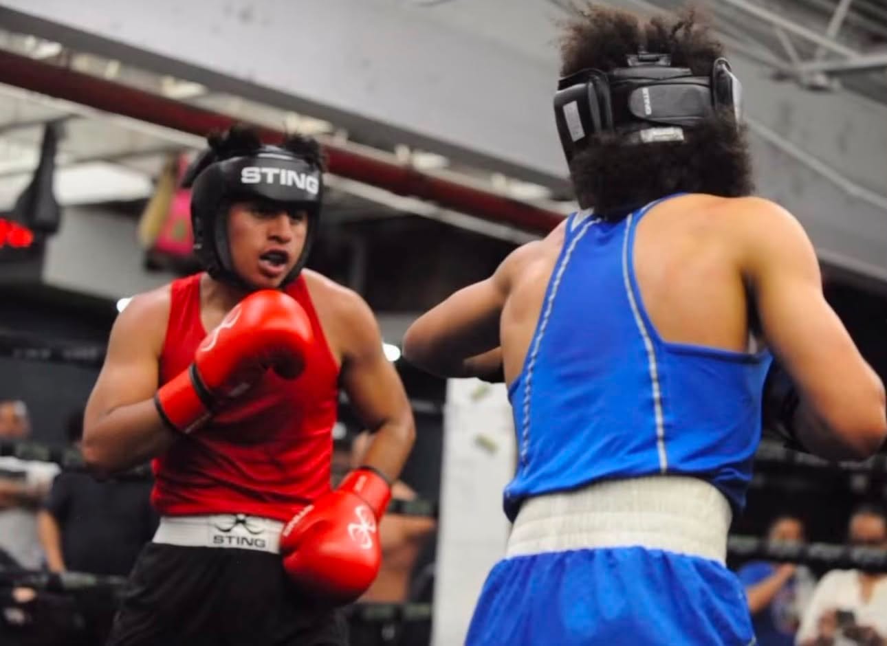 Dos boxeadores amateur con casco intercambiando golpes en una pelea oficial