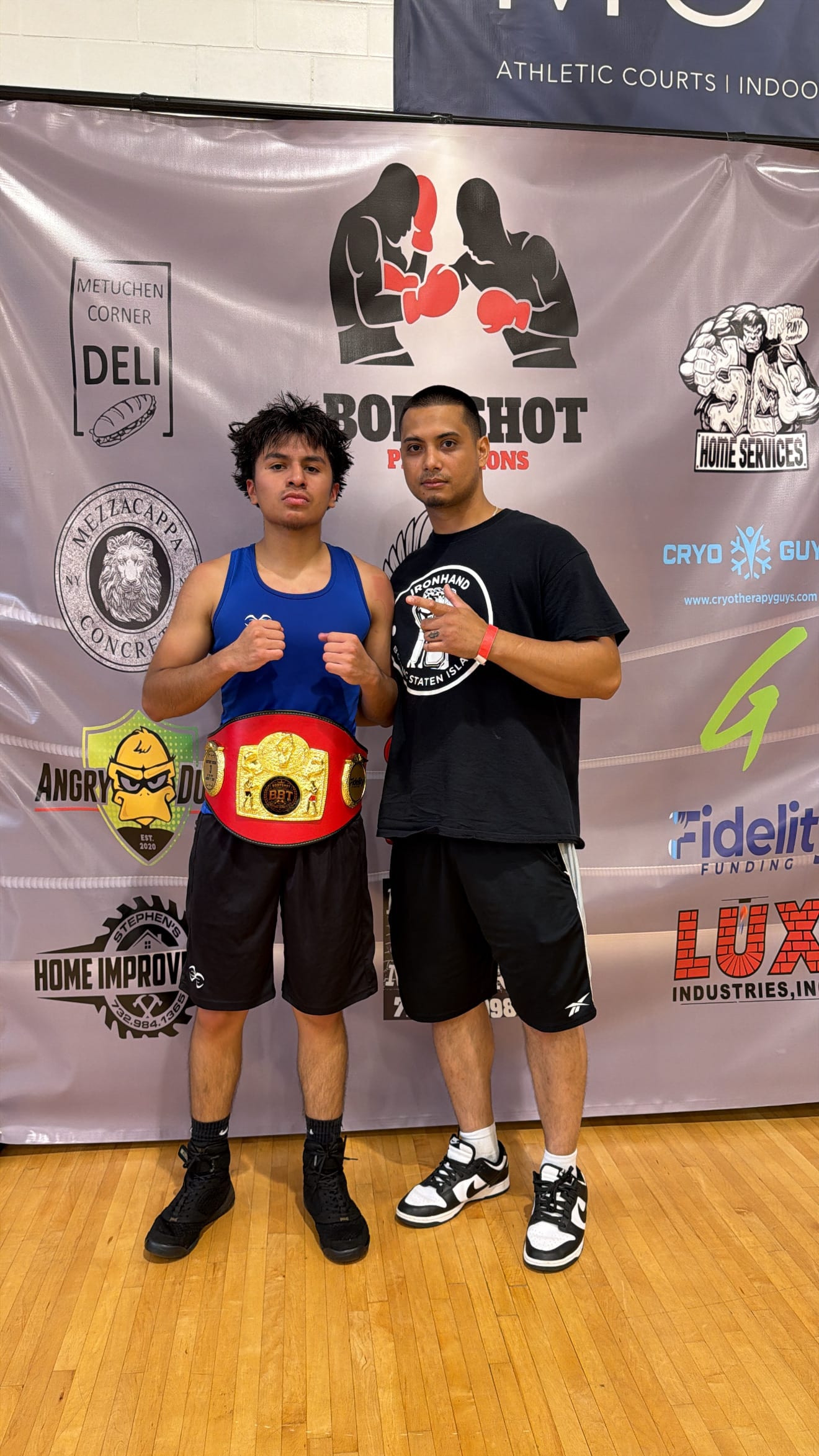 Un boxeador de Ironhand con su cinturón de campeón junto a su entrenador después de una pelea