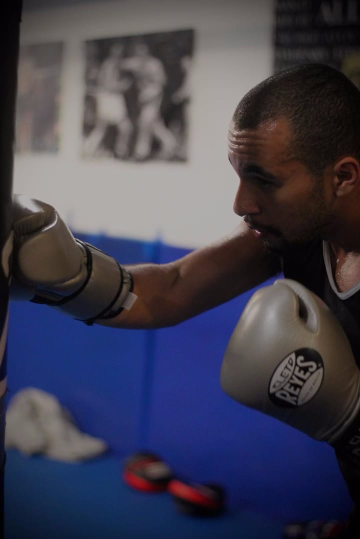 Primer plano de unos guantes de boxeo durante el trabajo de manoplas sobre las colchonetas de Ironhand Boxing