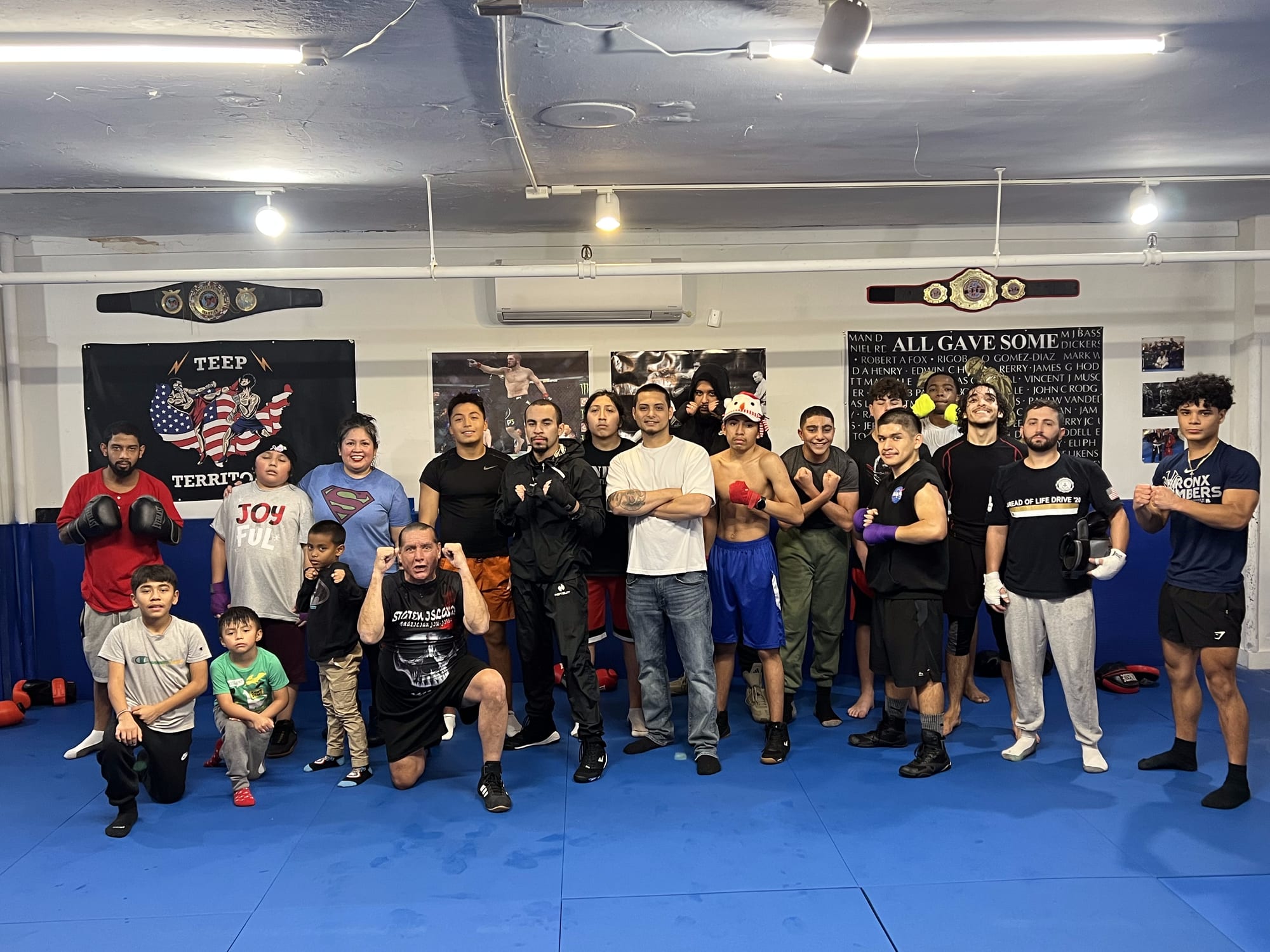 La comunidad de Ironhand Boxing, adultos y niños juntos en el piso del gimnasio en Staten Island