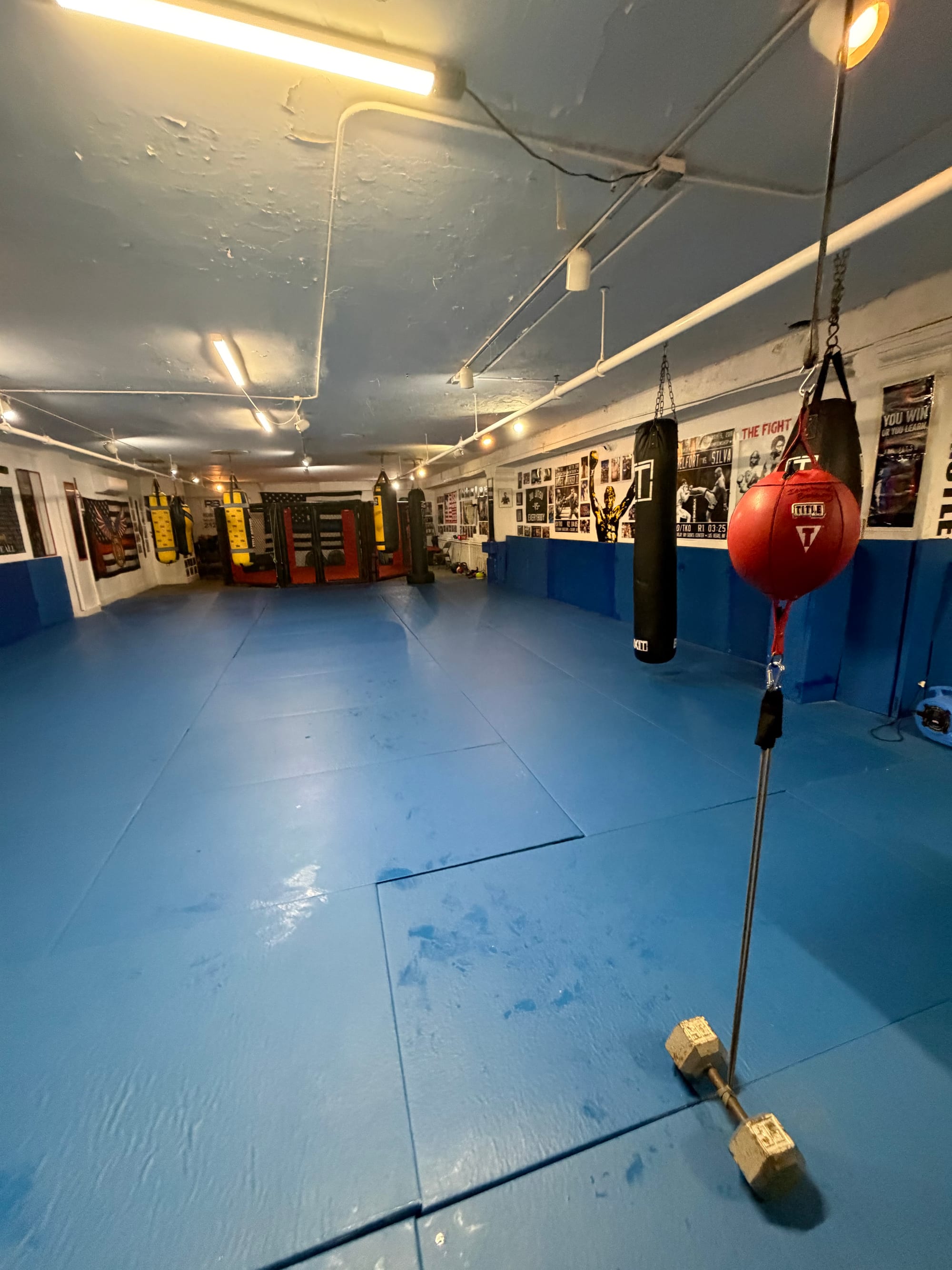 Sacos pesados y un saco de doble extremo en el piso de entrenamiento de Ironhand Boxing