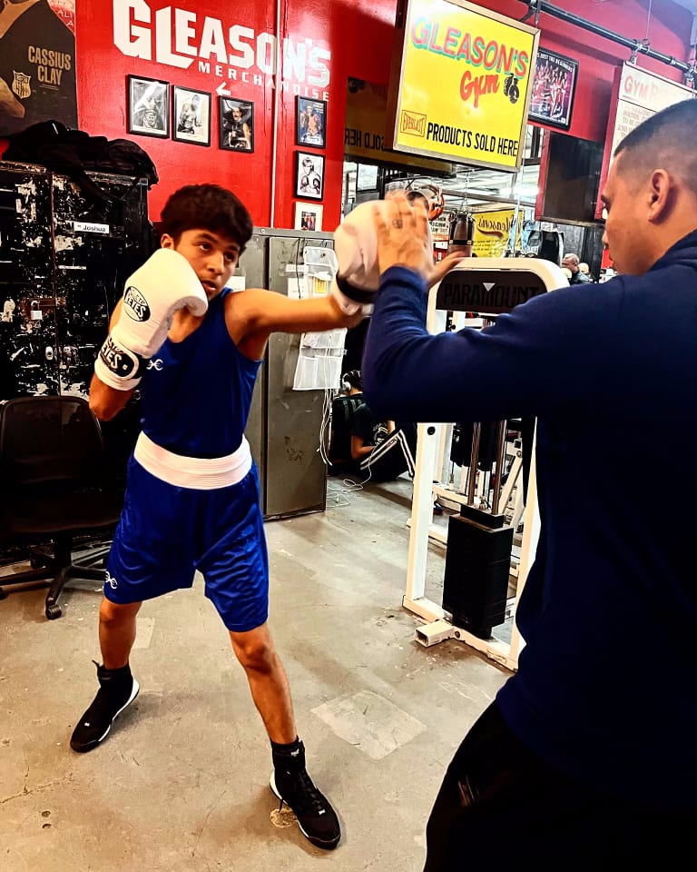 Un joven boxeador de Ironhand tirando una derecha recta en las manoplas con su entrenador